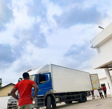 A confident man in a red t-shirt and khaki pants stands with hands on hips, overseeing operations be