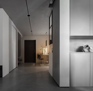 A modern apartment featuring gray flooring, white cabinetry, and a dark doorway.
