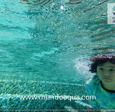 a young girl swimming in a pool with a blue shirt