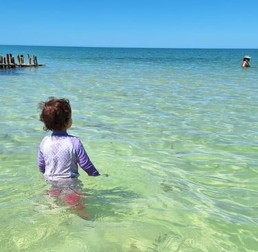 a child in the water with a man in the background