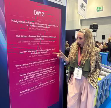 a woman standing in front of a sign that says Elysian Services HR Ltd speaker slot at Accountex