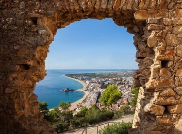 Vista panorámica de Blanes con restaurantes cerca de la playa y una pareja disfrutando de una comida