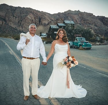 a man and woman holding hands and walking down a road