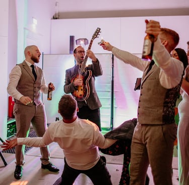groom and groomsmen dancing with guitar wedding party band