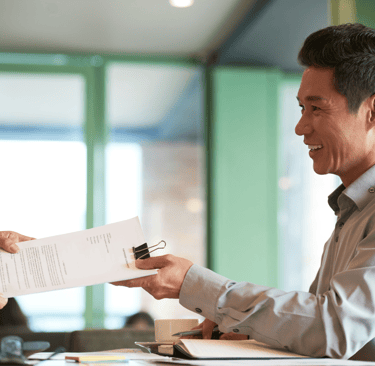 a man in a suit and tie is handing a permit document to a woman