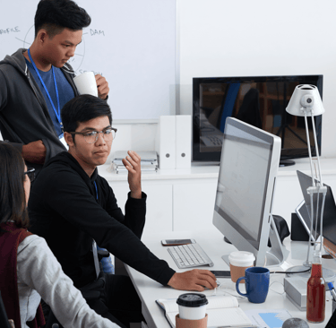 a man and woman sitting at a desk with a laptop