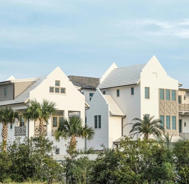Luxury white coastal villas with palm trees and modern architecture under a blue sky.