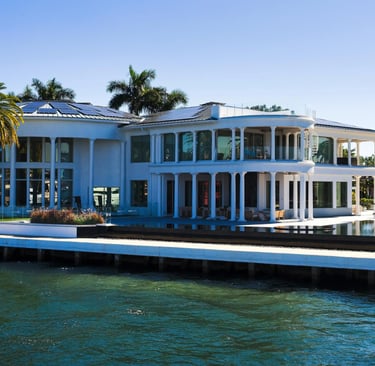 a large house with a dock and palm trees