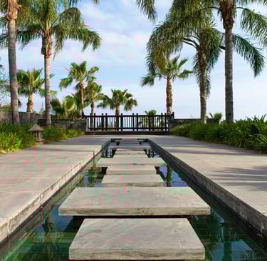 a stone path leading to a pool with stepping stones