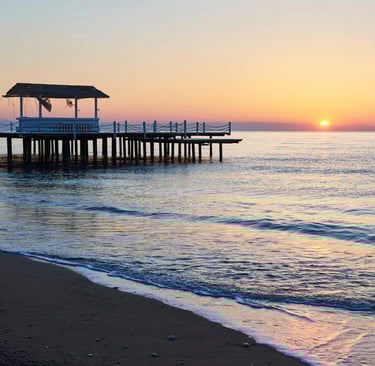 sunset on a beach next to a dock
