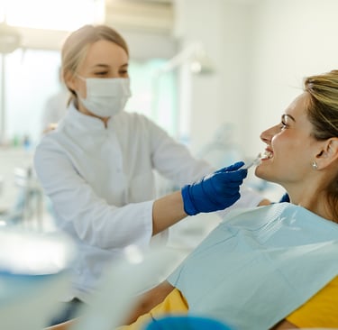 A professional dentist performing a dental checkup on a female patient in a modern dental clinic.