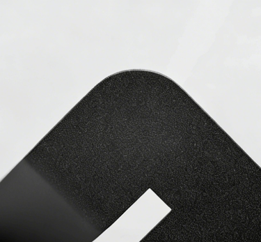 Close-up of a matte black textured metal surface with a rounded corner and a white cutout detail.