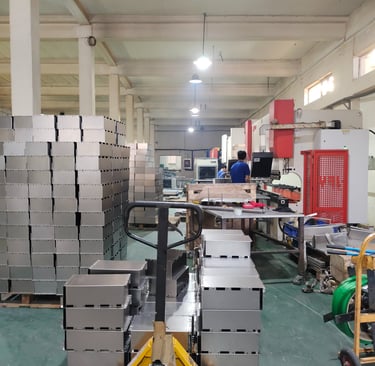 Pallet jack moving stacked stainless steel enclosures in a precision metal fabrication factory.