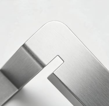 Close-up of a brushed stainless steel metal corner joint with a precision notch design.