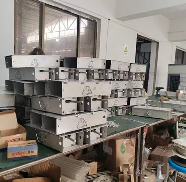 Worker assembling stainless steel sheet metal enclosures in a factory production line.
