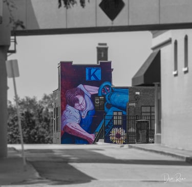 Urban mural of a labor figure on the Kansan Building, with selective color against a grayscale streetscape.