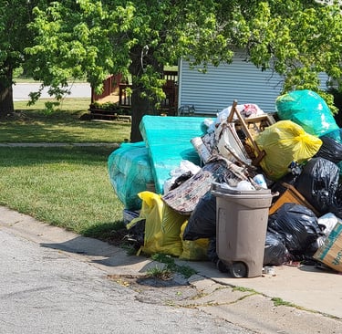 Large curbside pile of bagged trash, furniture, and bulky household items in Kansas City, Kansas.