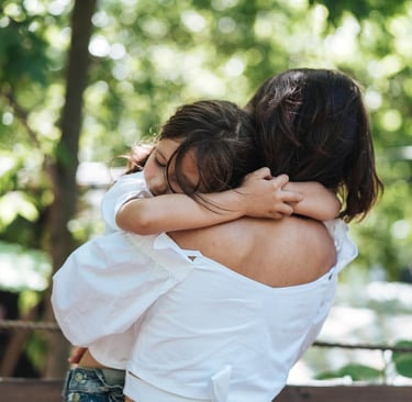a woman in a white shirt is hugging her daughter