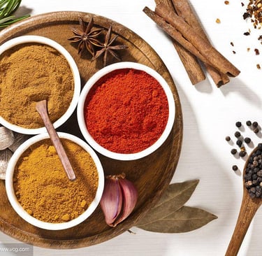 Variety of colorful organic spices including turmeric, paprika, and curry powder in bowls with cinnamon sticks.