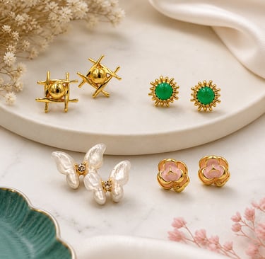 Collection of elegant gold stud earrings including pearl butterflies, green sunbursts, and pink flowers.