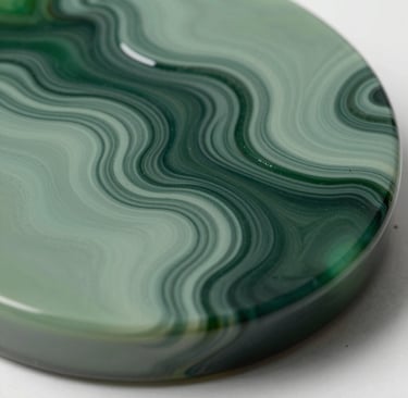 Macro photography of a fluid resin art piece with swirling textures in deep forest green and muted sage green. The surface is glass-like and glossy, reflecting soft studio lighting. Elegant and modern composition.