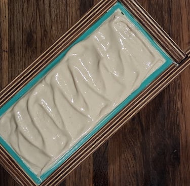 Handmade soap batter with textured peaks in a wooden loaf mold with a teal silicone liner.