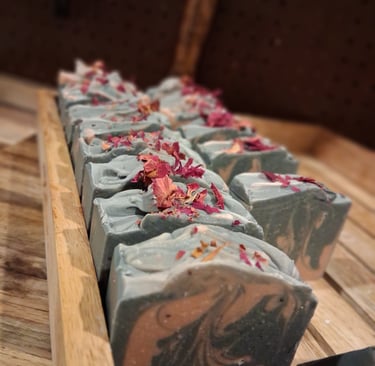 Handmade artisan soap bars with floral petals on a wooden tray for natural skincare.
