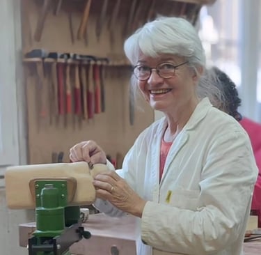 Eveline David-Valette, sculptrice sur bois, utilisant des outils manuels dans son atelier.