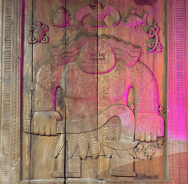 Polynesian wood carving of Maui holding a fishhook, featuring tribal tattoos and ocean animal motifs.