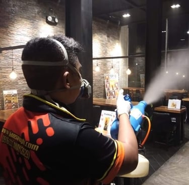 Professional pest control technician sanitizing a restaurant interior with a fogging machine and mask.