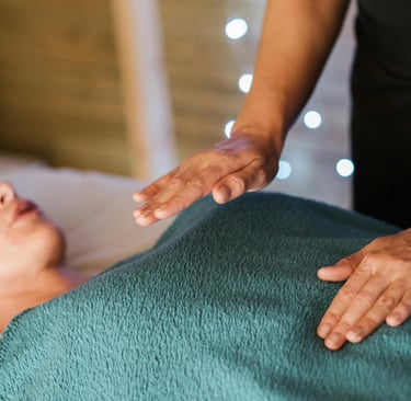 Une femme reçoit une séance de magnétisme, allongée sur une table de massage, détendue et concentrée.