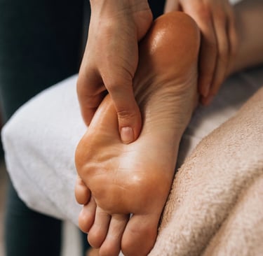 Une personne bénéficiant d'une séance de réflexologie, détendue, assise sur une chaise avec un thérapeute à ses pieds.