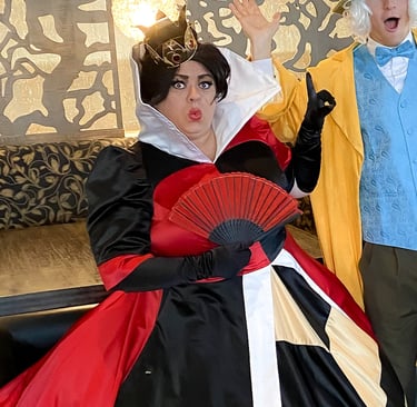 A Queen of Hearts character holding a red fan and wearing a gold crown.