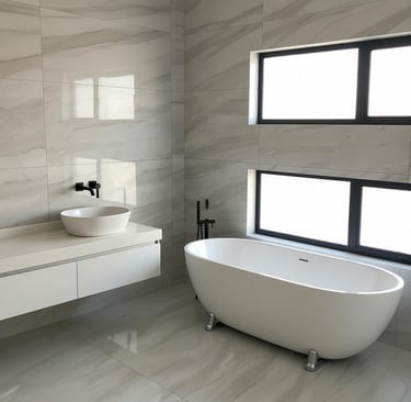 Modern bathroom with a freestanding bathtub, vessel sink, and marble-look porcelain tile walls.