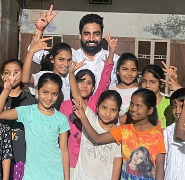 Vikash Sharma with a group of cheerful young girls making peace signs at a school or community center