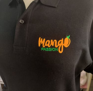 A black polo shirt featuring an embroidered orange and green Mango Passion logo on the chest.