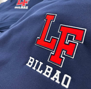 Close-up of a navy blue hoodie featuring a red and white embroidered LF Bilbao varsity logo.