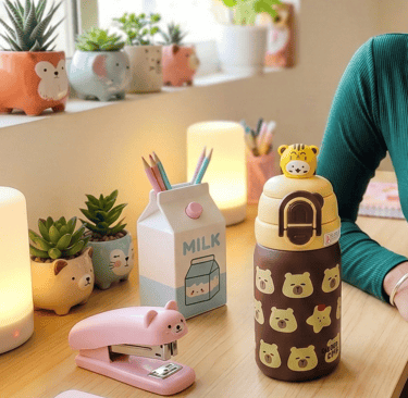 Aesthetic brown animal-themed water bottle on a desk next to a pink stapler and warm lighting