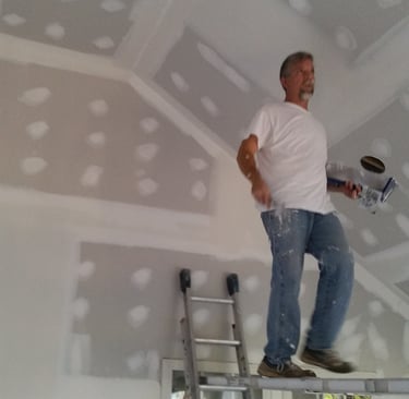 Daryl Graybill finishing a ceiling while on a scaffold walk board.