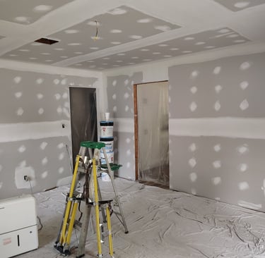 A room that we skim coated with drywall compound with stilts standind up against a ladder.