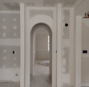 An interior home renovation featuring newly installed arched doorways and smooth finished drywall.