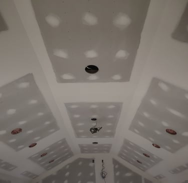 Vaulted tray ceiling with finished drywall and joint compound mudding during home construction.