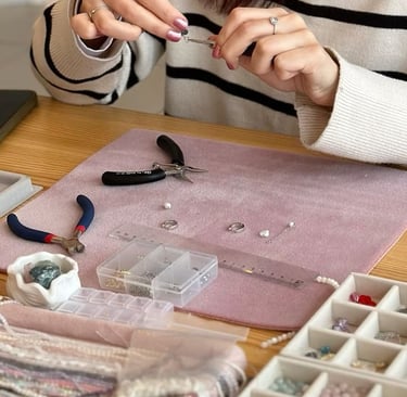 Artesana de joyería utilizando pinzas para ensamblar aretes de cuentas hechos a mano