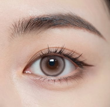 Close-up of a brown colored contact lens on a woman's eye with natural makeup and eyeliner.