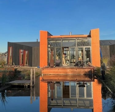 Fachada da casa sustentável prefabricada em CLT com a piscina natural no primeiro plano