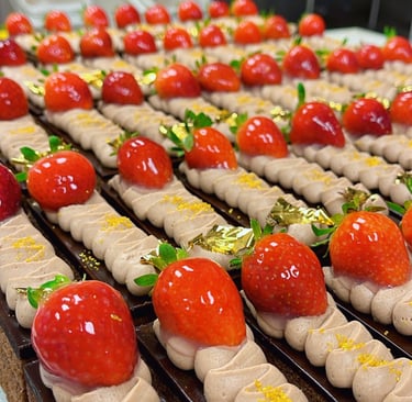 Gourmet chocolate cake slices topped with mocha cream, fresh glazed strawberries, and edible gold leaf.