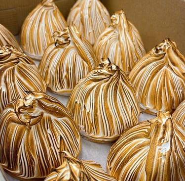 Gourmet toasted meringue tarts with golden brown peaks arranged in a bakery pastry box.
