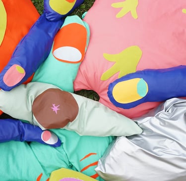 Soft sculptures of fingers, eyes, a tongue and a neuron displayed on grass on a hot sunny day.