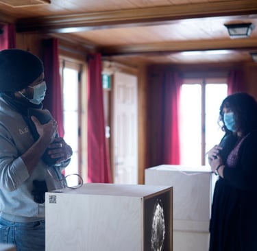 Two people hold vibrating cushions with brain waves in front of light boxes sharing MS stories.