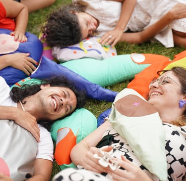 Quatre personnes allongées sur des sculptures souples de parties du corps.